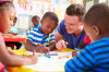 Volunteer-teacher-helping-a-class-of-preschool-kids-drawing-484793580